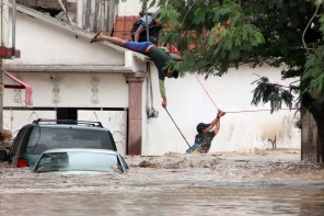 epa03871453 A rescue worker climbs across a line to help trapped people in Chailpanchingo, Mexico, 17 September 2013. According to media reports, Hurricane Ingrid was downgraded to a tropical storm but continued to pour heavy rain over eastern Mexico, where it killed at least 34 people. EPA/LENIN OCAMPO TORRES